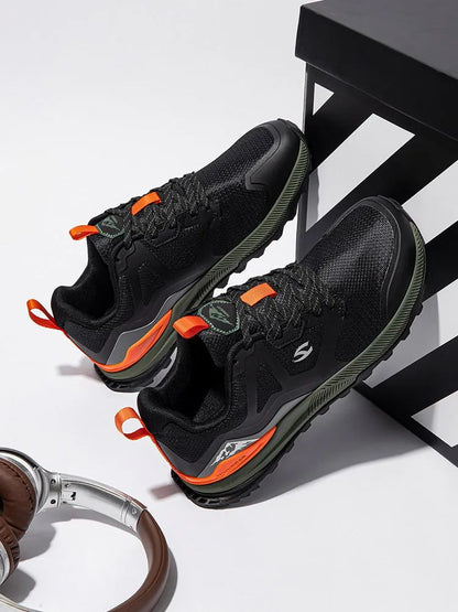 Black athletic shoes with orange accents on a white surface