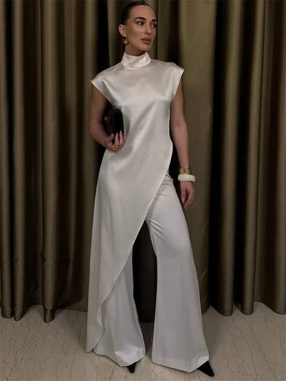 Woman in a white dress standing against a brown curtain