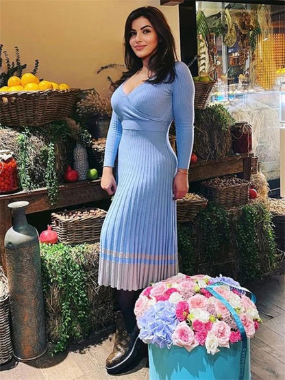 Woman in a blue dress standing in a market setting with flowers and produce.