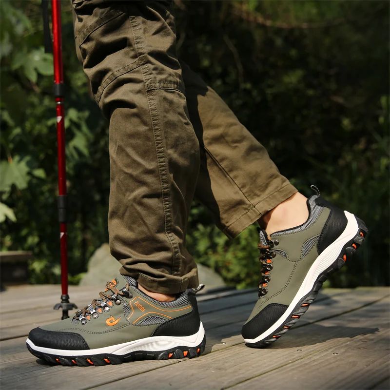 Person wearing green hiking shoes with orange accents on a wooden deck with a blurred natural background