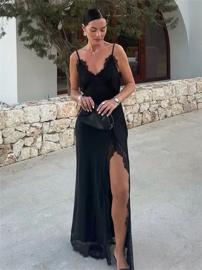 Woman wearing a black lace dress with a stone wall and tree in the background