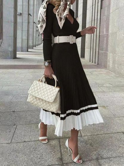 Woman in a stylish outfit with a black and white dress, white handbag, and patterned scarf in an urban setting.