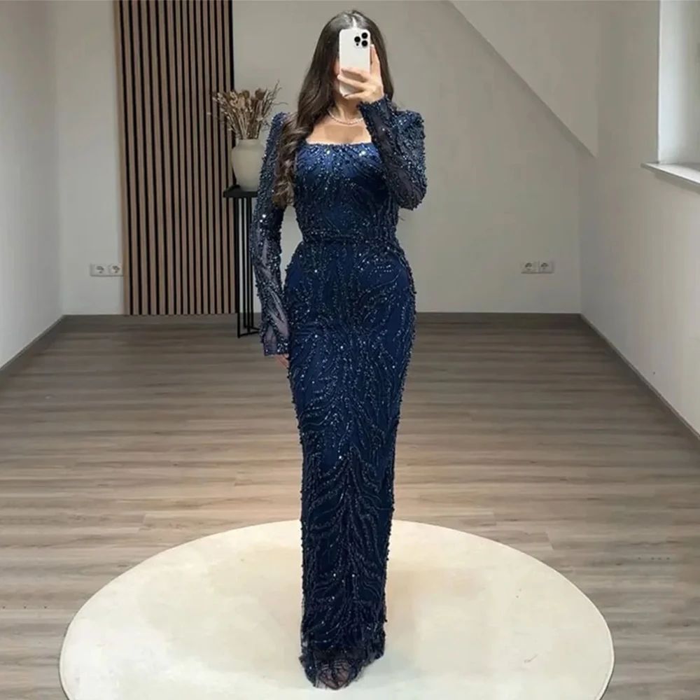 Woman wearing a blue beaded evening gown taking a mirror selfie.