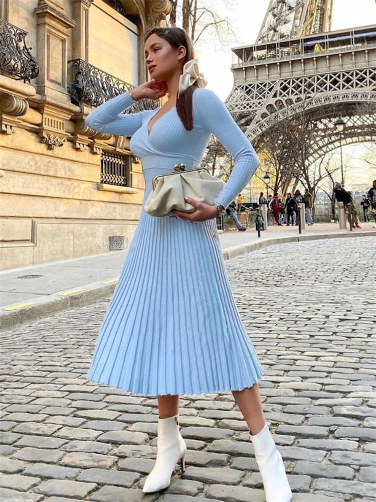 Woman in a light blue dress standing in front of the Eiffel Tower.