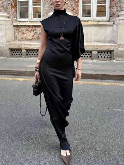 Person wearing a black outfit with a high collar on a street.