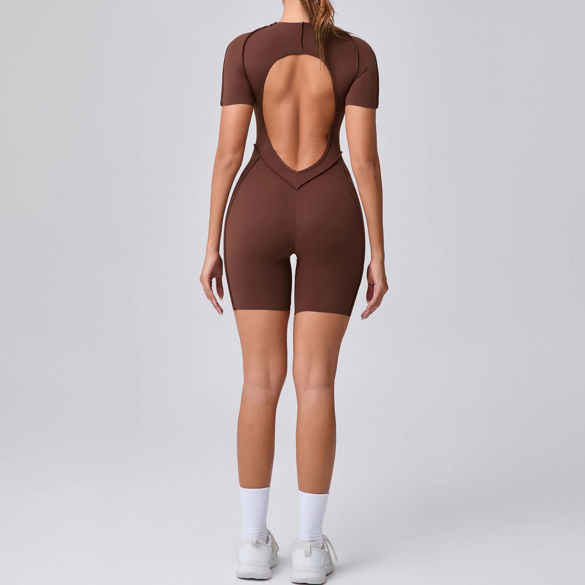 Brown open-back bodysuit worn by a model on a gray background