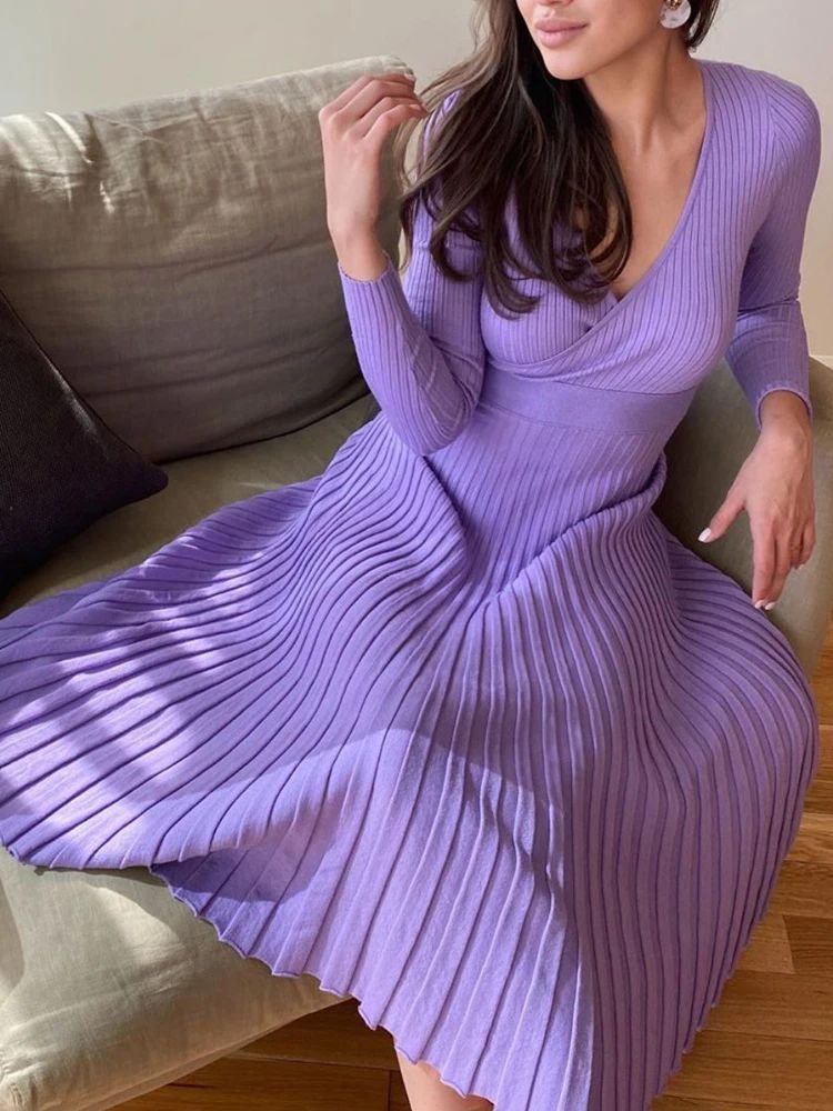 Woman wearing a purple ribbed dress sitting on a couch.