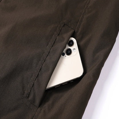 Smartphone peeking out from a pocket of dark brown pants on a white background