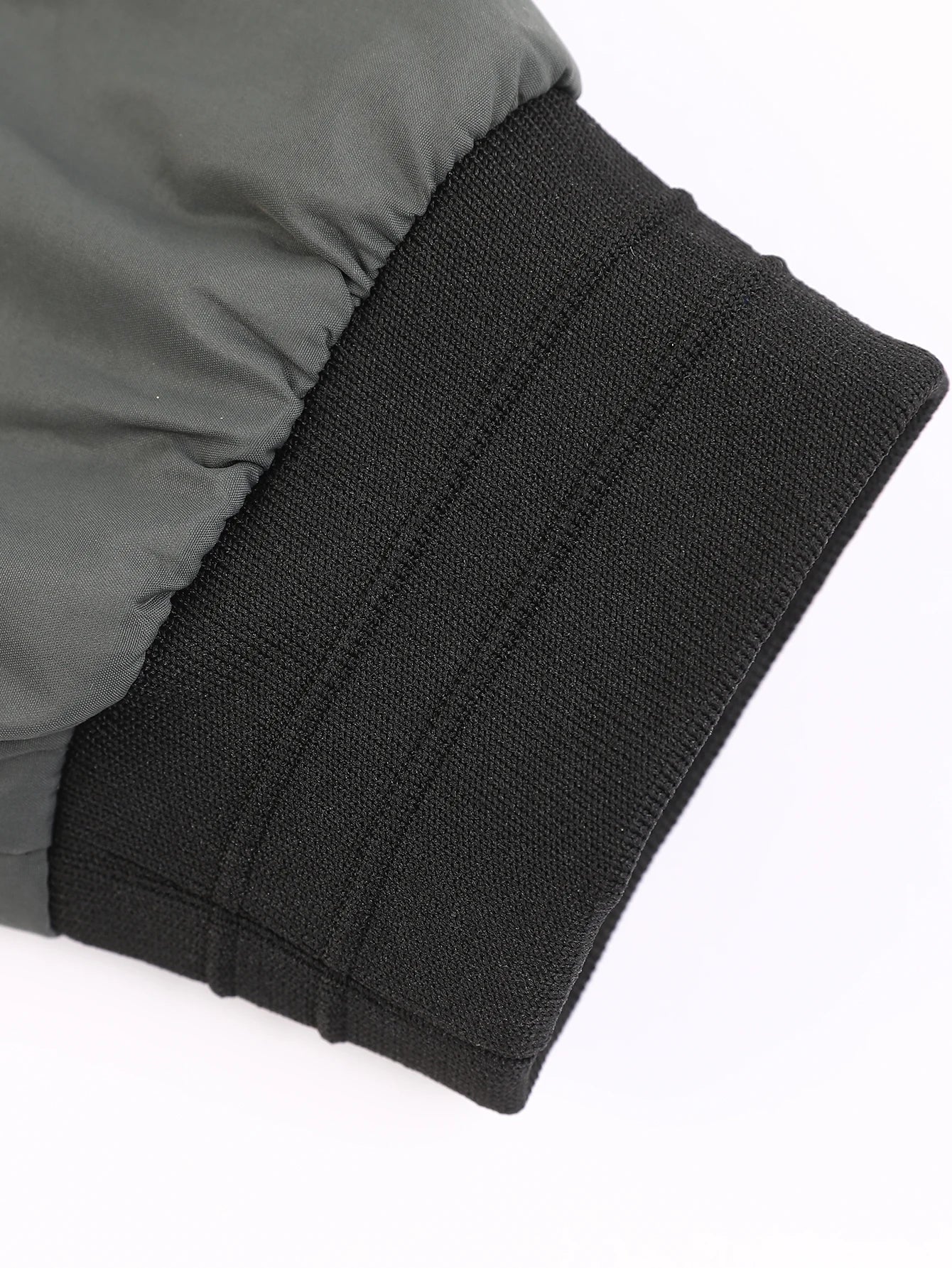 Close-up of a gray jacket with black ribbed cuffs on a white background