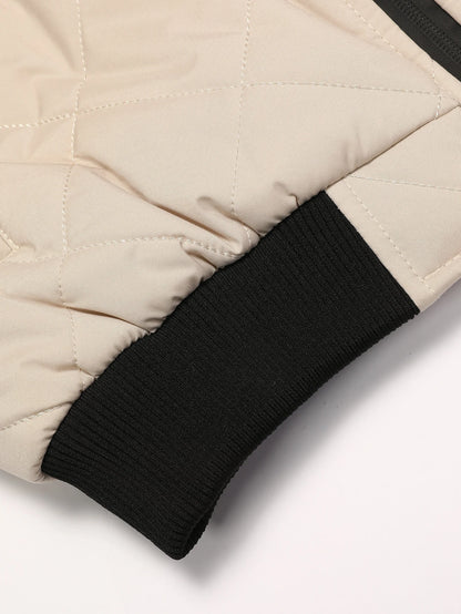 Close-up of a beige quilted jacket with black ribbed cuffs on a white background