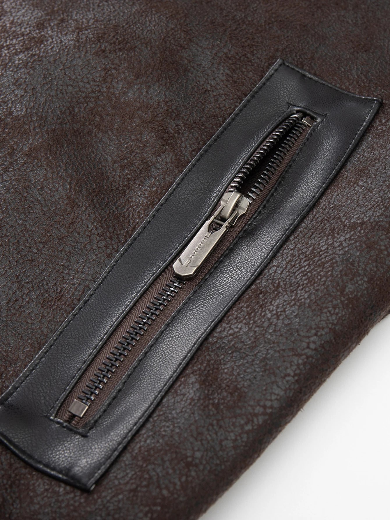 Close-up of a dark brown leather jacket with a zipper on a white background