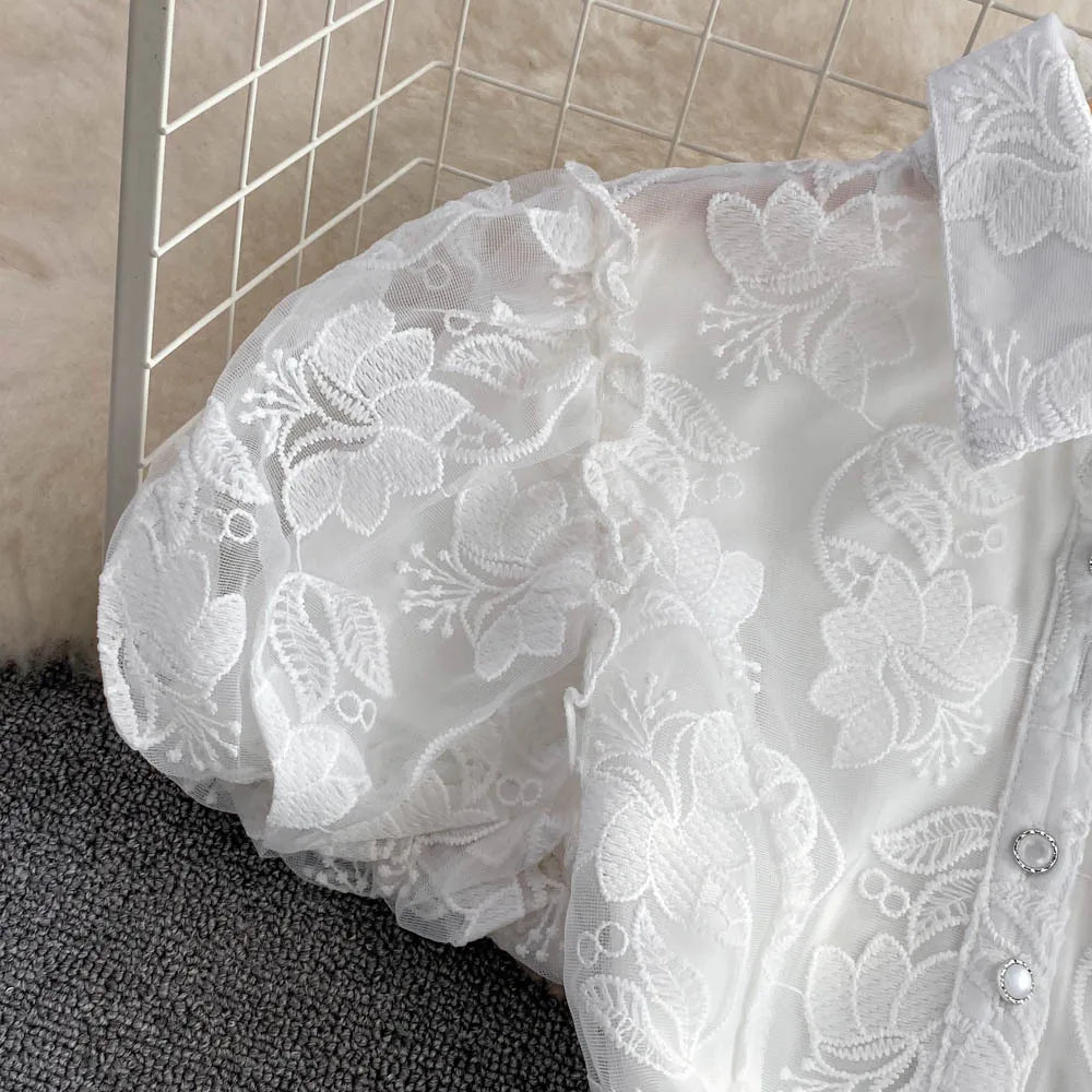 Close-up of a white lace garment on a textured surface with tiled wall in the background.