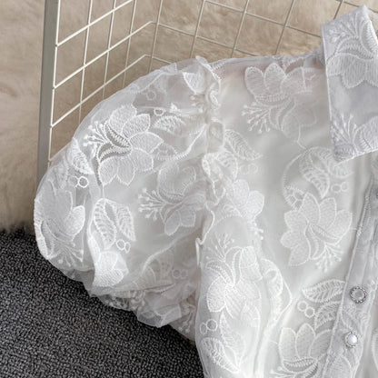 Close-up of a white lace garment on a textured surface with tiled wall in the background.