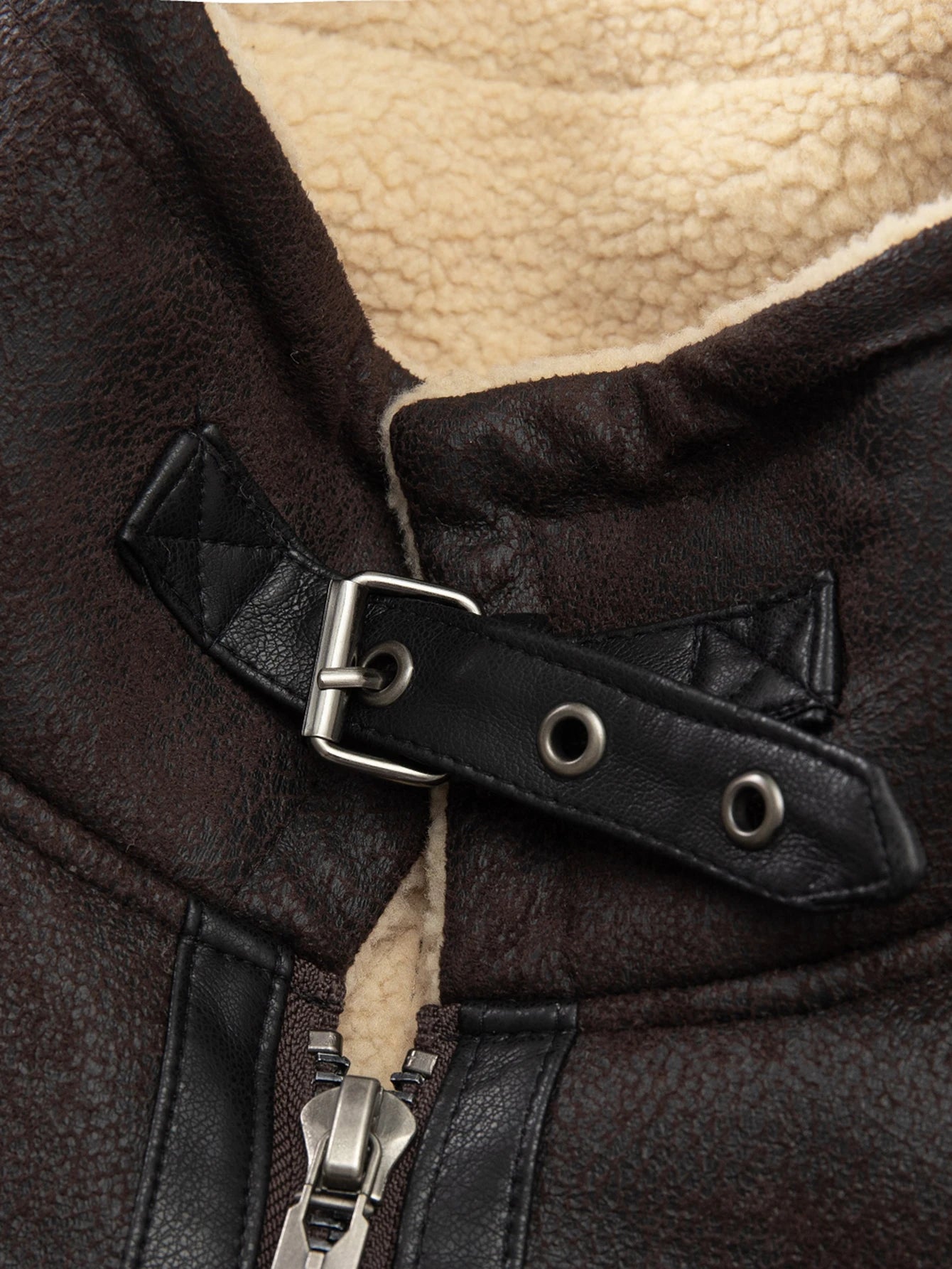 Close-up of a brown leather coat with a zipper and buckle detail.
