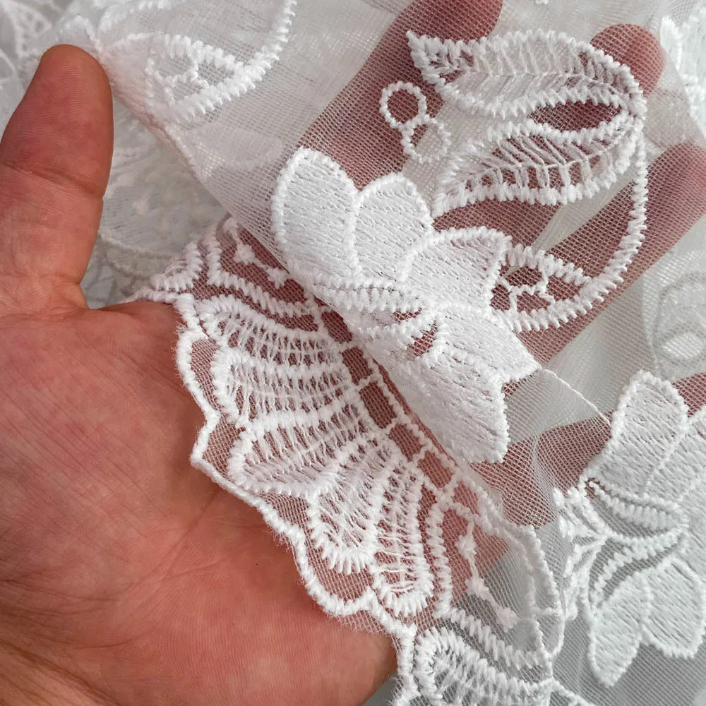 Close-up of white lace fabric held between fingers