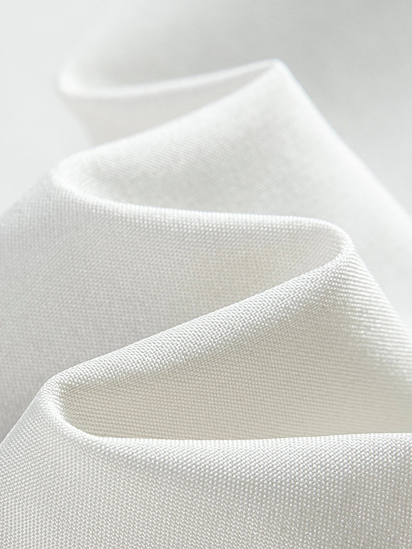 Close-up of white fabric with a textured pattern on a light gray background