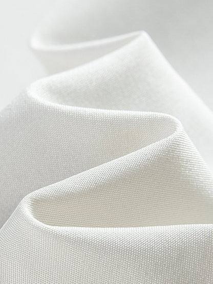 Close-up of white fabric with a textured pattern on a light gray background