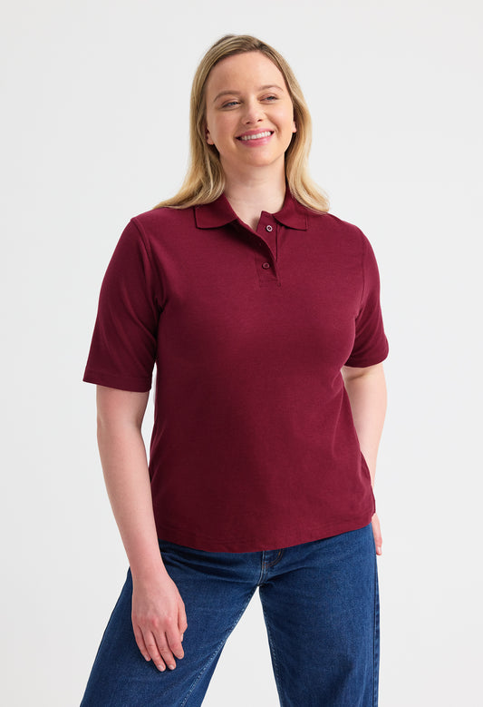 Woman wearing a maroon polo shirt and blue jeans on a white background