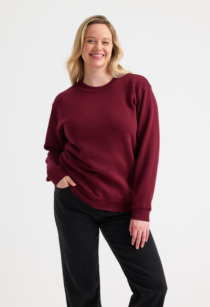 Woman wearing a burgundy sweater and black pants on a white background