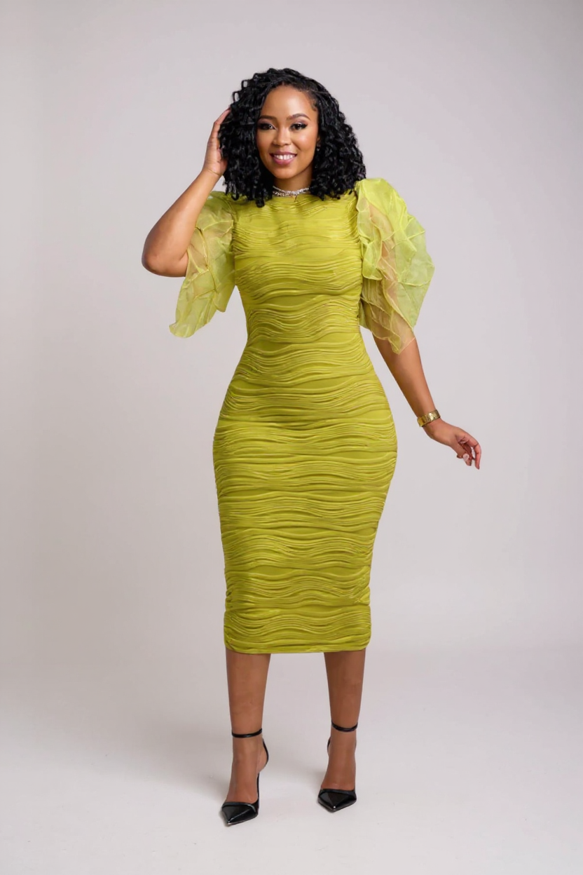 Woman wearing a green dress with sheer sleeves against a white background