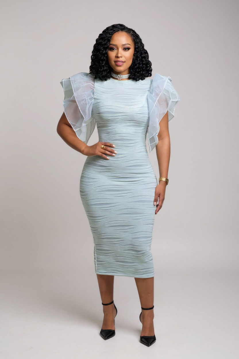 Woman wearing a light blue dress with sheer sleeves against a plain background