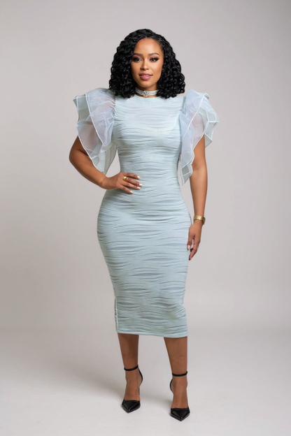 Woman wearing a light blue dress with sheer sleeves against a plain background