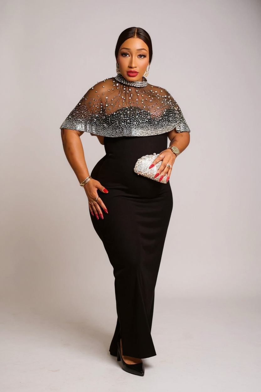 Woman wearing a black dress with a sheer silver top against a plain background