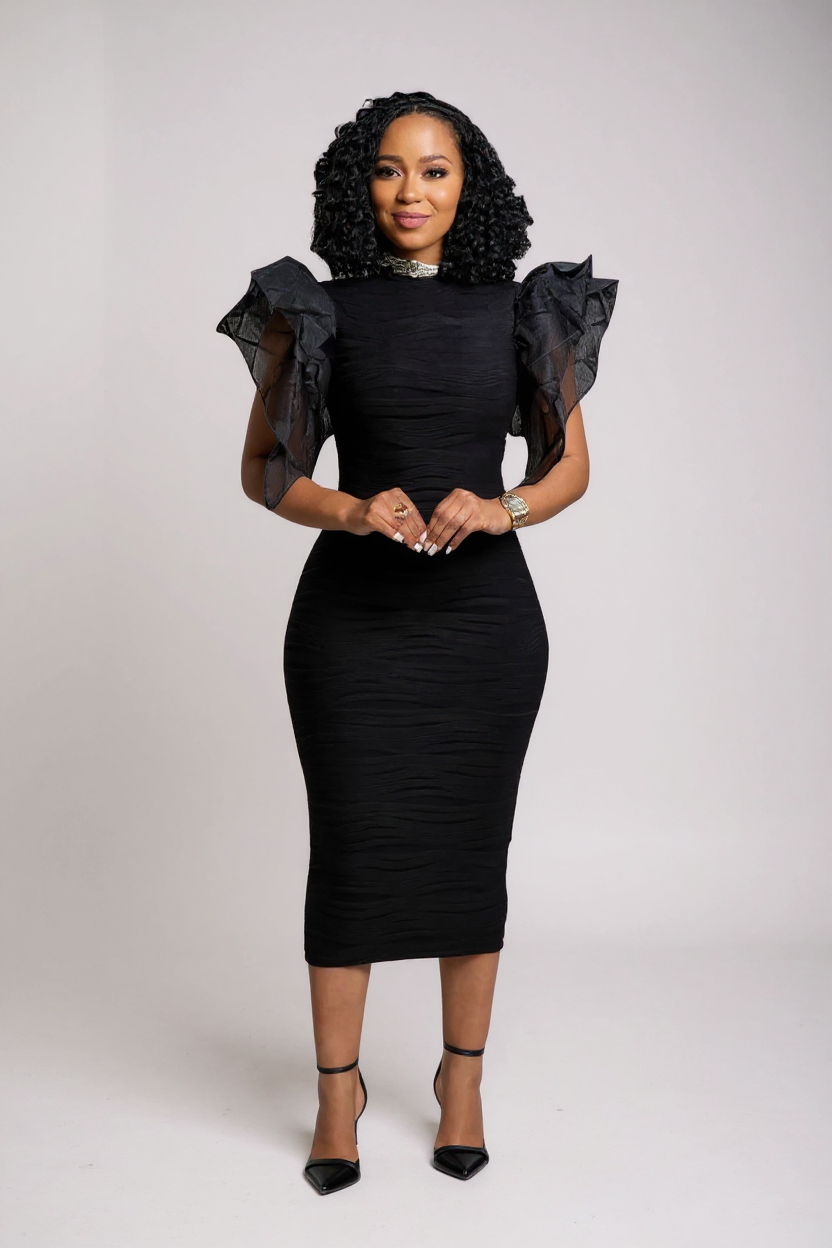 Woman wearing a black dress with ruffled shoulders against a white background